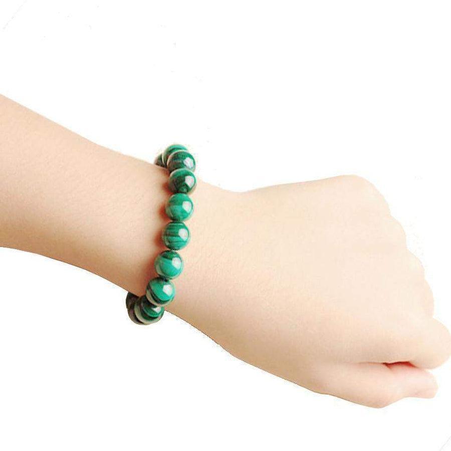 Bracelet bouddhiste en malachite synthétique posé sur une surface