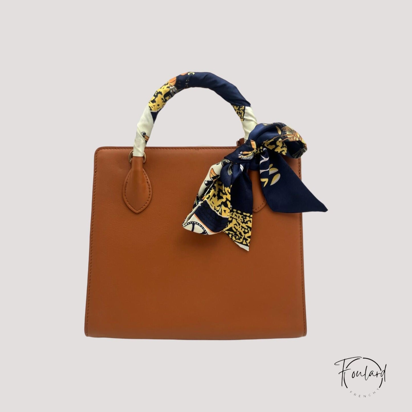 Gros plan sur motifs équestres dorés et ivoire du foulard