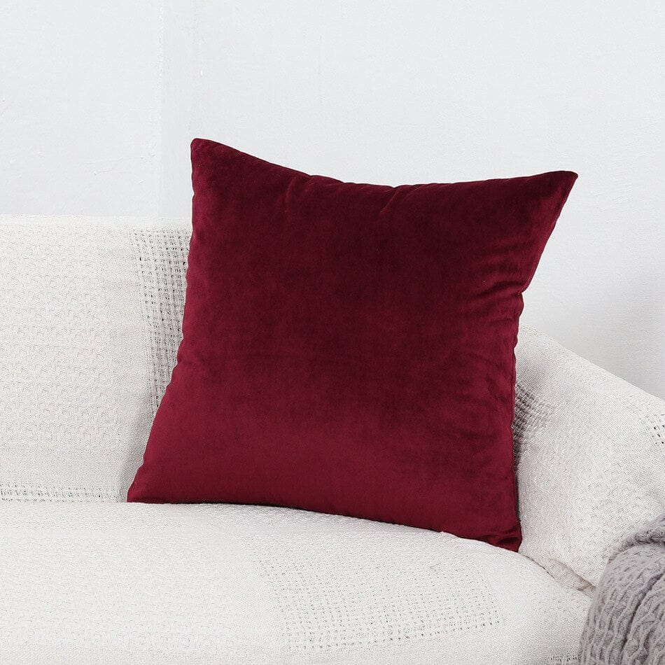 Deux housses de coussin bordeaux en velours extensible sur canapé