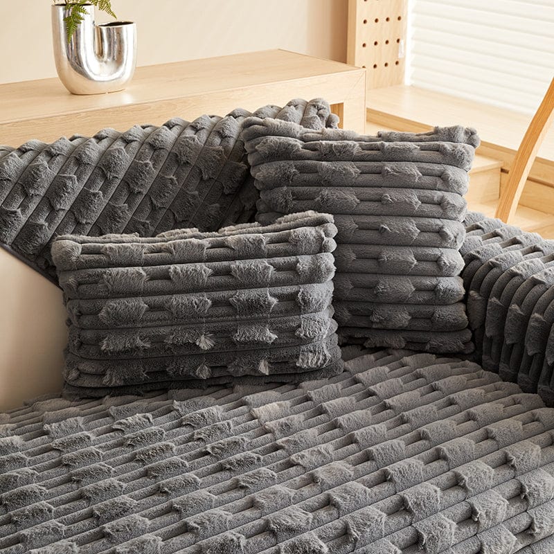 Housse de coussin en fausse fourrure grise sur canapé