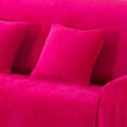 Deux housses de coussin en velours rose sur un canapé