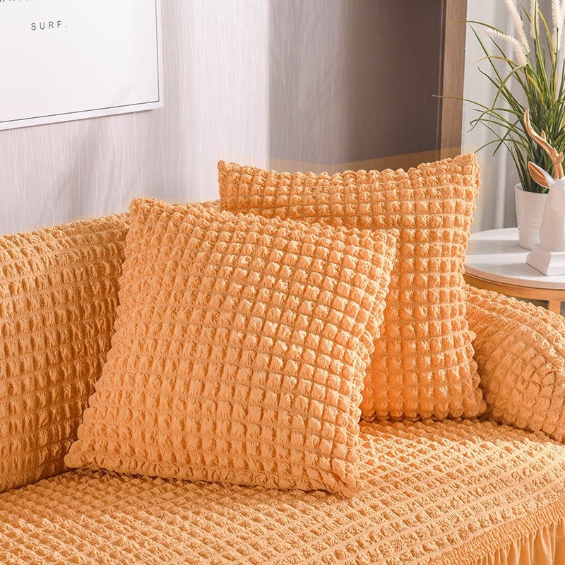 Deux housses de coussin saumon en tissu extensible sur canapé