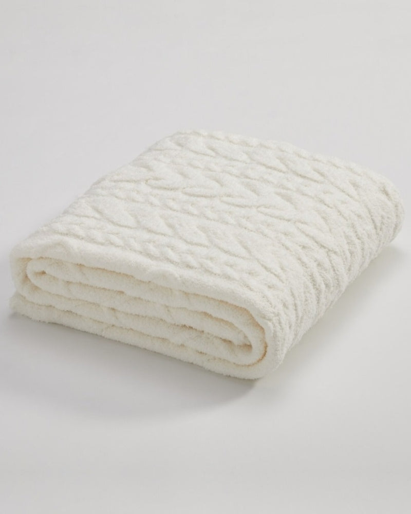 Plaid blanc avec motifs ethniques, posé sur un fauteuil