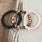 Trois bracelets en quartz rose, onyx et rhodonite sur fond blanc