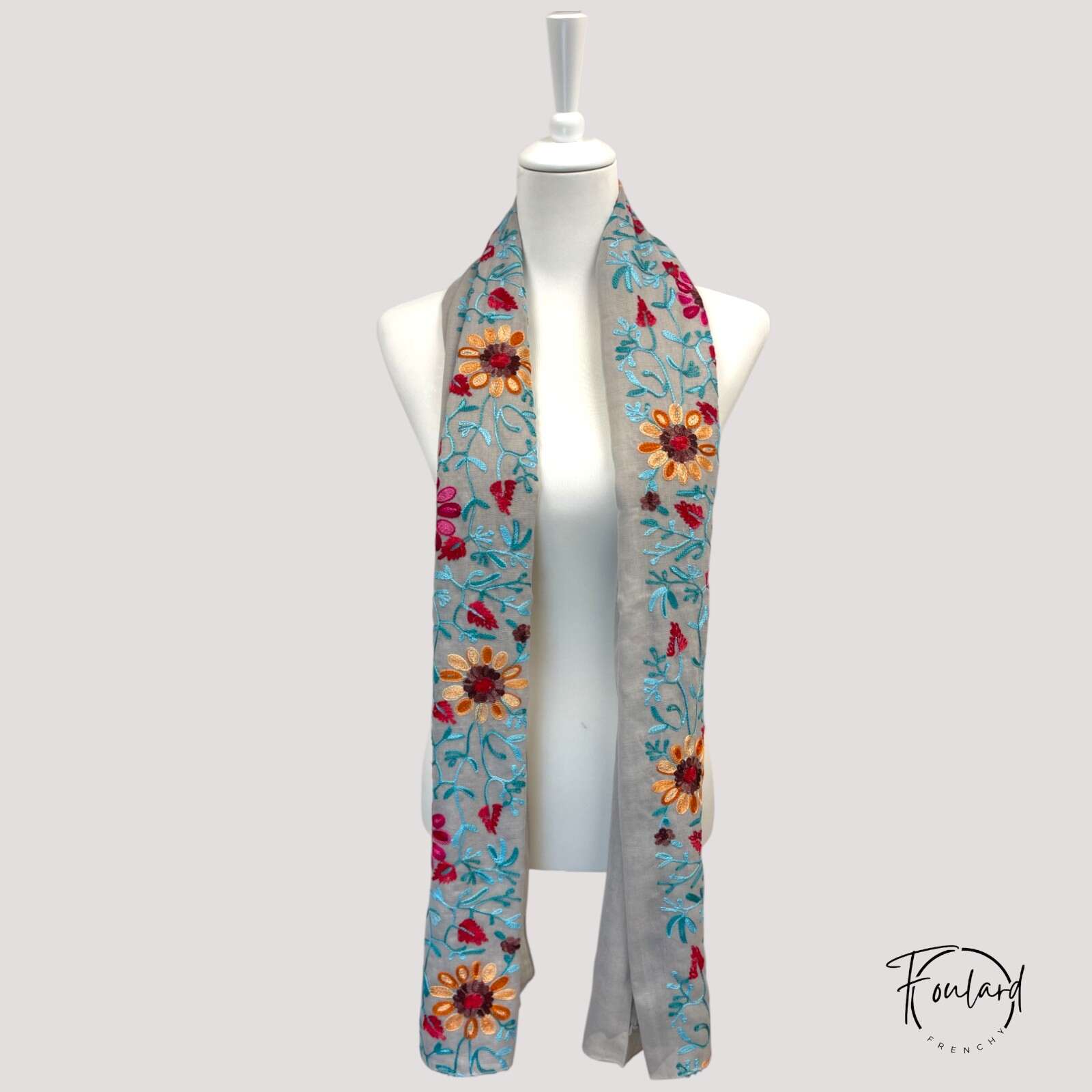 Détail des broderies fuchsia, orange et turquoise sur foulard
