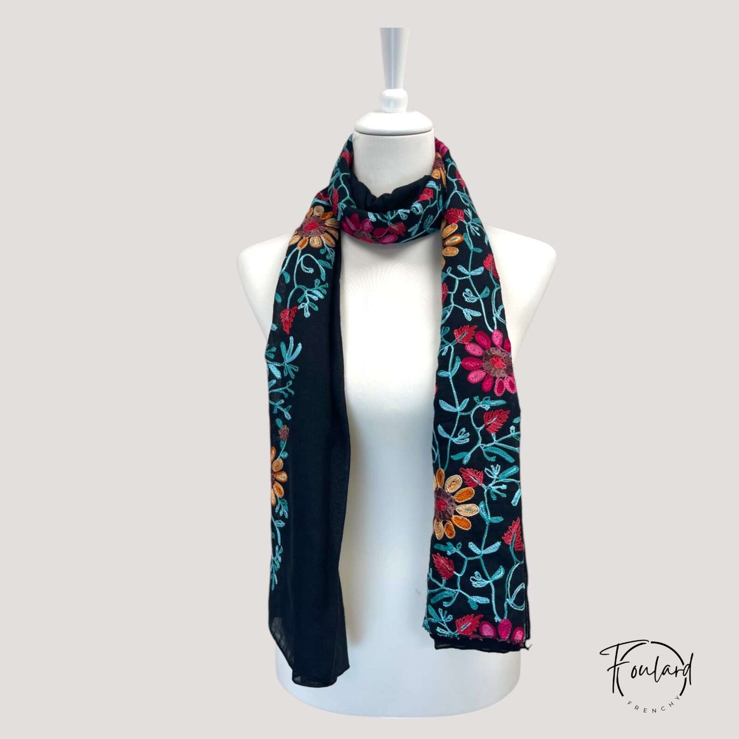 Détail des broderies florales sur tissu noir fluide