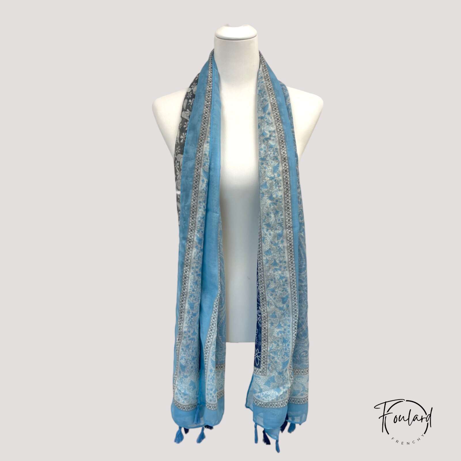 Détail des pompons frangés sur foulard bleu satiné