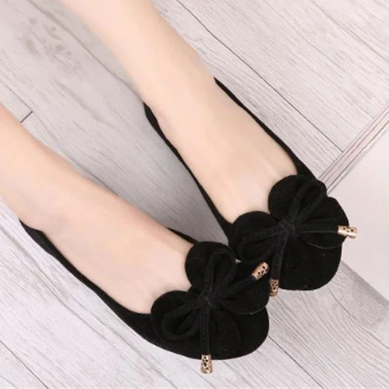 Ballerines avec nœud et embouts dorés sur fond blanc