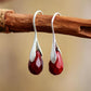 Boucles d'oreilles pendantes avec pierres rouges et support argenté