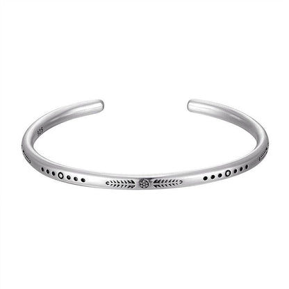 Bracelet jonc argenté avec motifs gravés, posé à plat