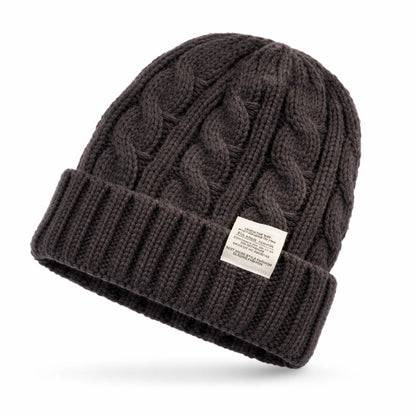 Bonnet en maille torsadée, posé sur un fond clair