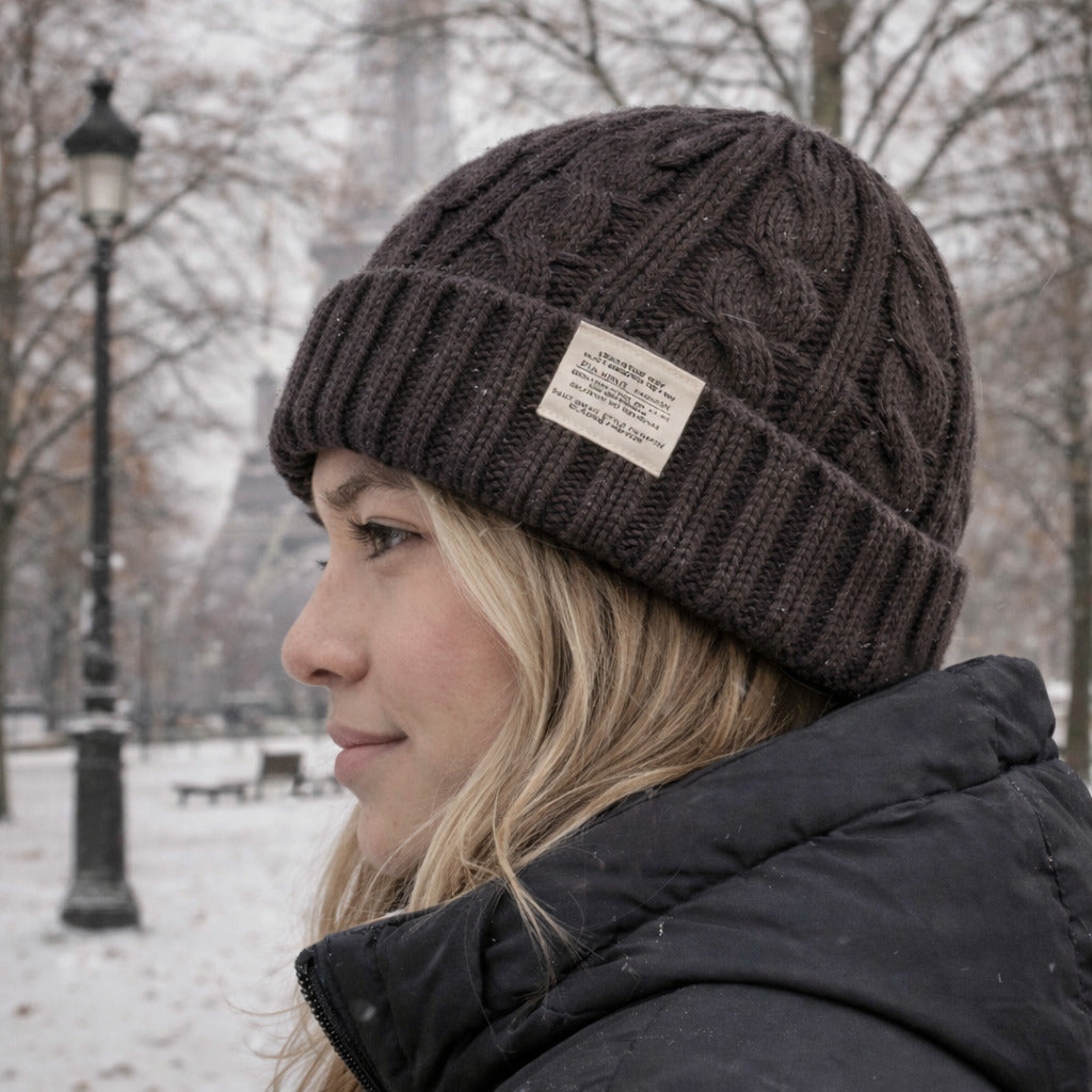 Bonnet en maille torsadée posé sur une surface en bois