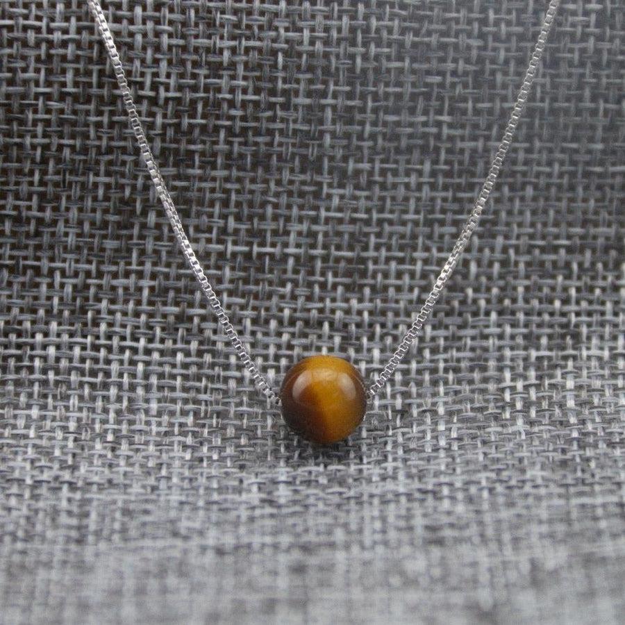 Collier Œil de tigre posé sur une surface claire