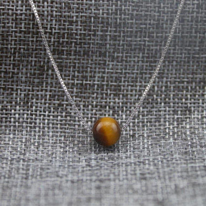 Collier Œil de tigre posé sur une surface claire
