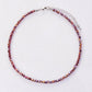 Collier multicolore en cristal, posé sur une surface blanche