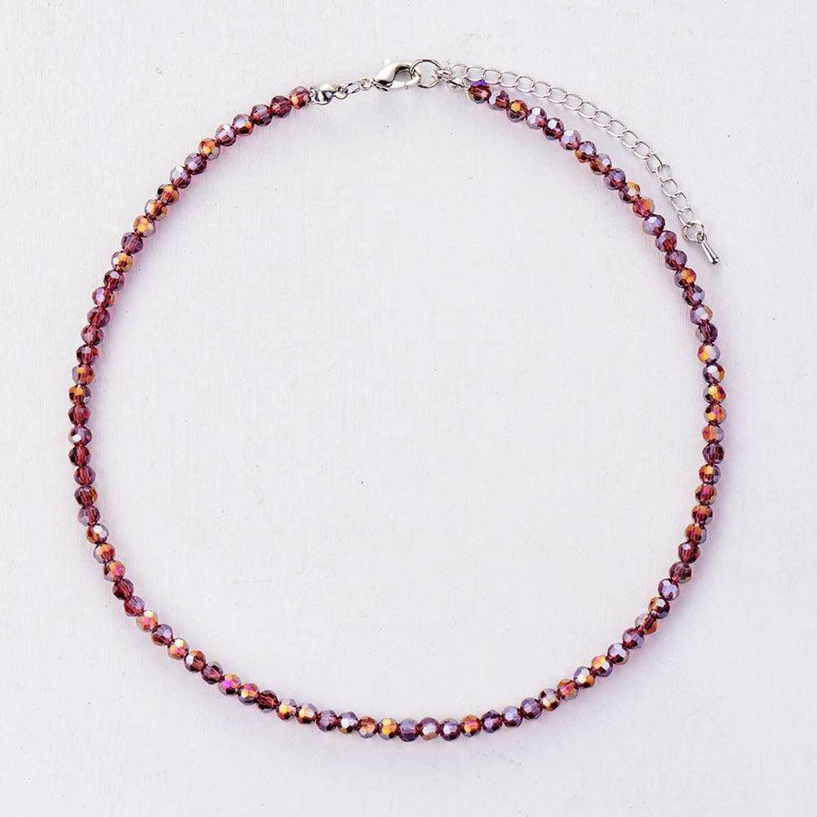 Collier multicolore en cristal, posé sur une surface blanche