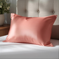 Taie d'oreiller en soie Coral sur un lit blanc