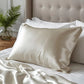 Taie d'oreiller en soie beige grège sur lit blanc