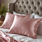 Taie d'oreiller en soie rose sur lit blanc