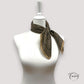 Foulard noué, texture douce et motifs noirs sur beige