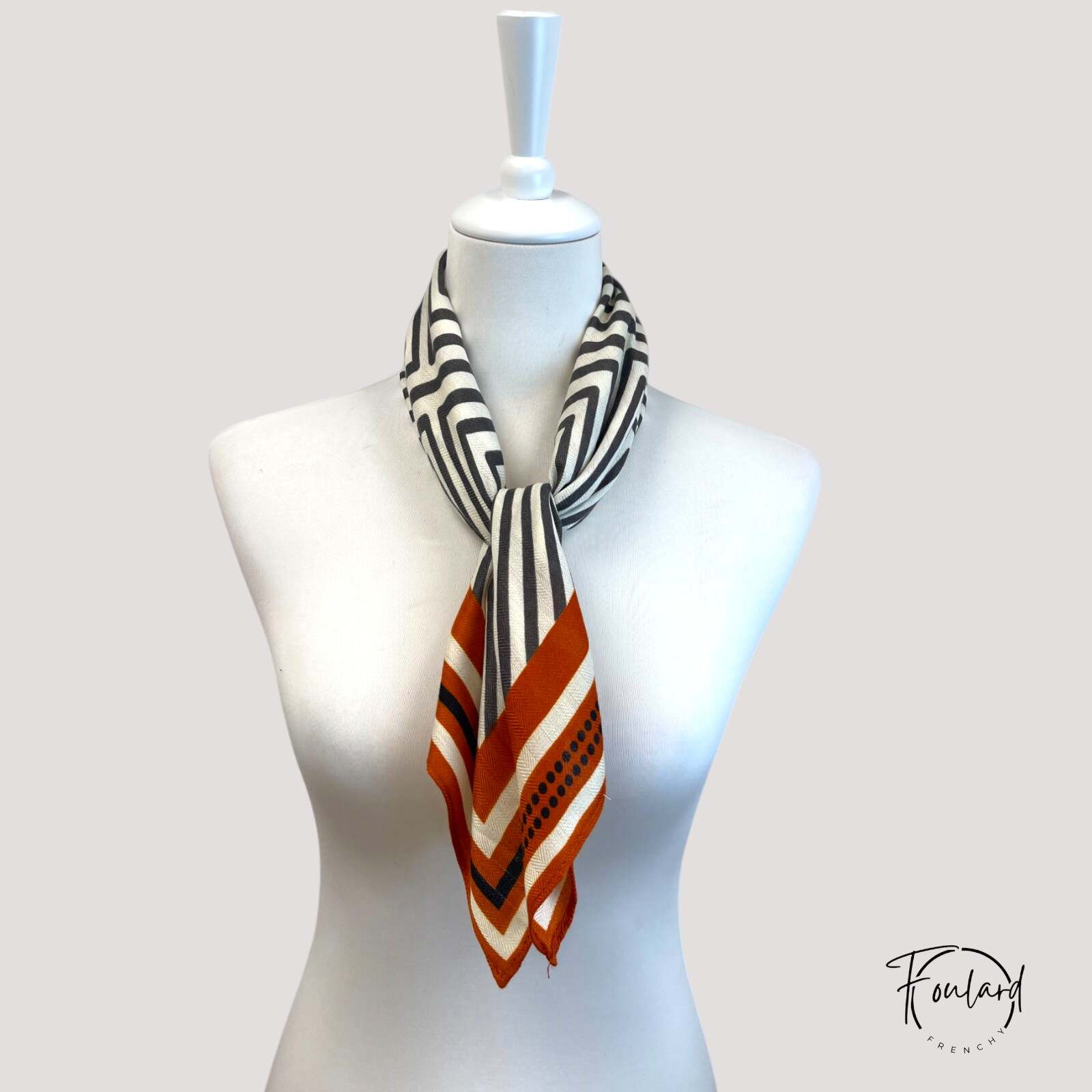 Gros plan sur les motifs chevrons rouille et noirs du foulard