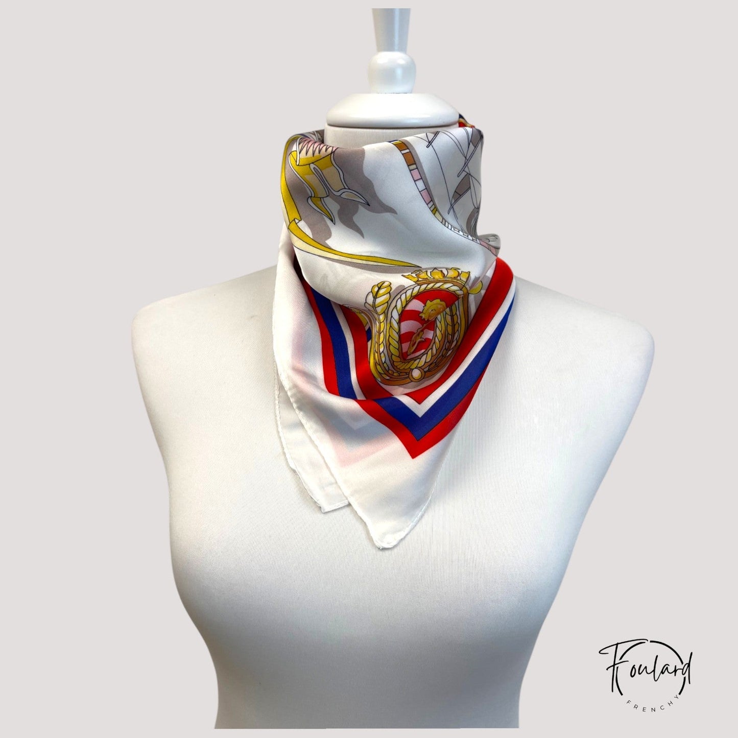 Foulard carré 70 cm enroulé sur une surface blanche