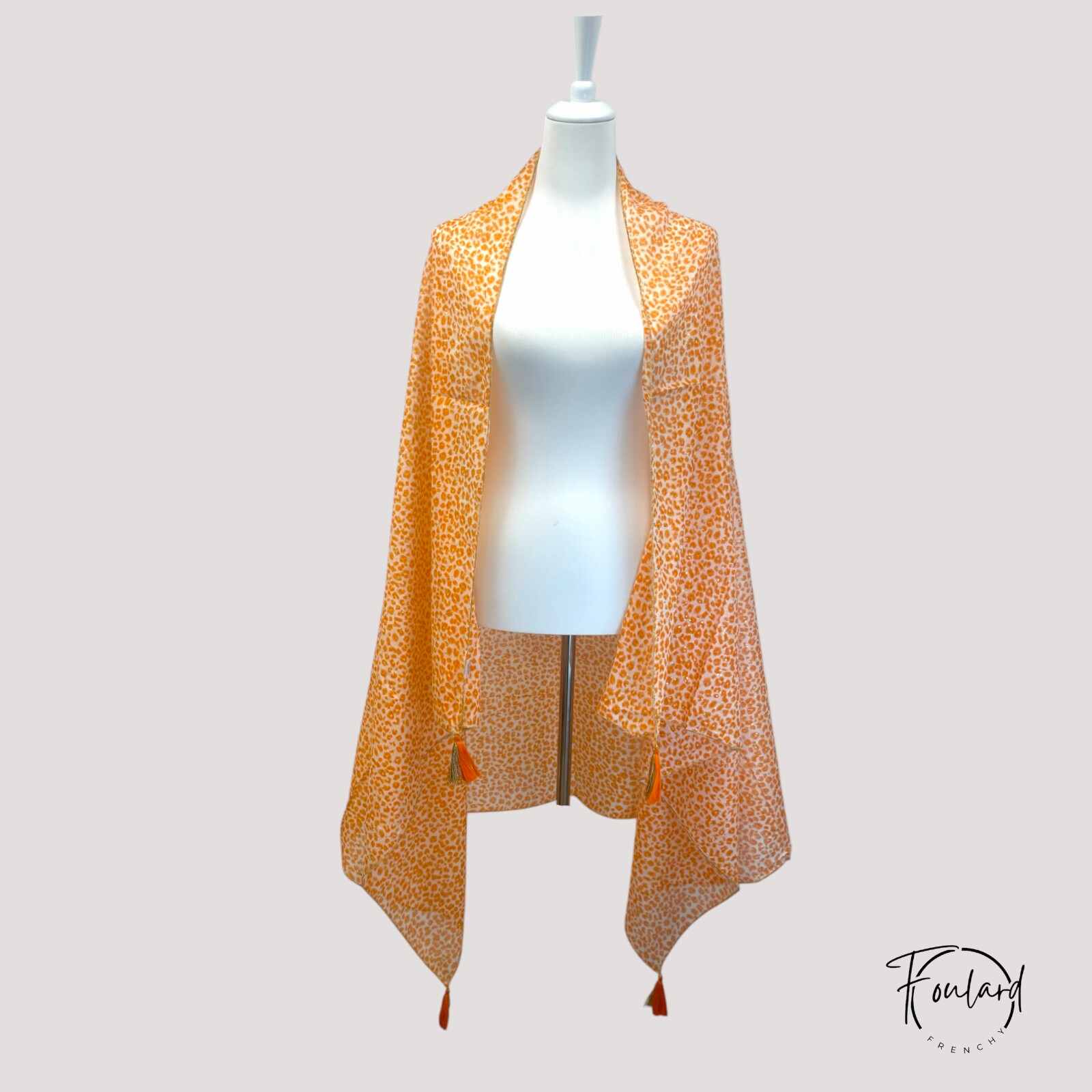 Foulard orange léopard avec pompons dorés en gros plan