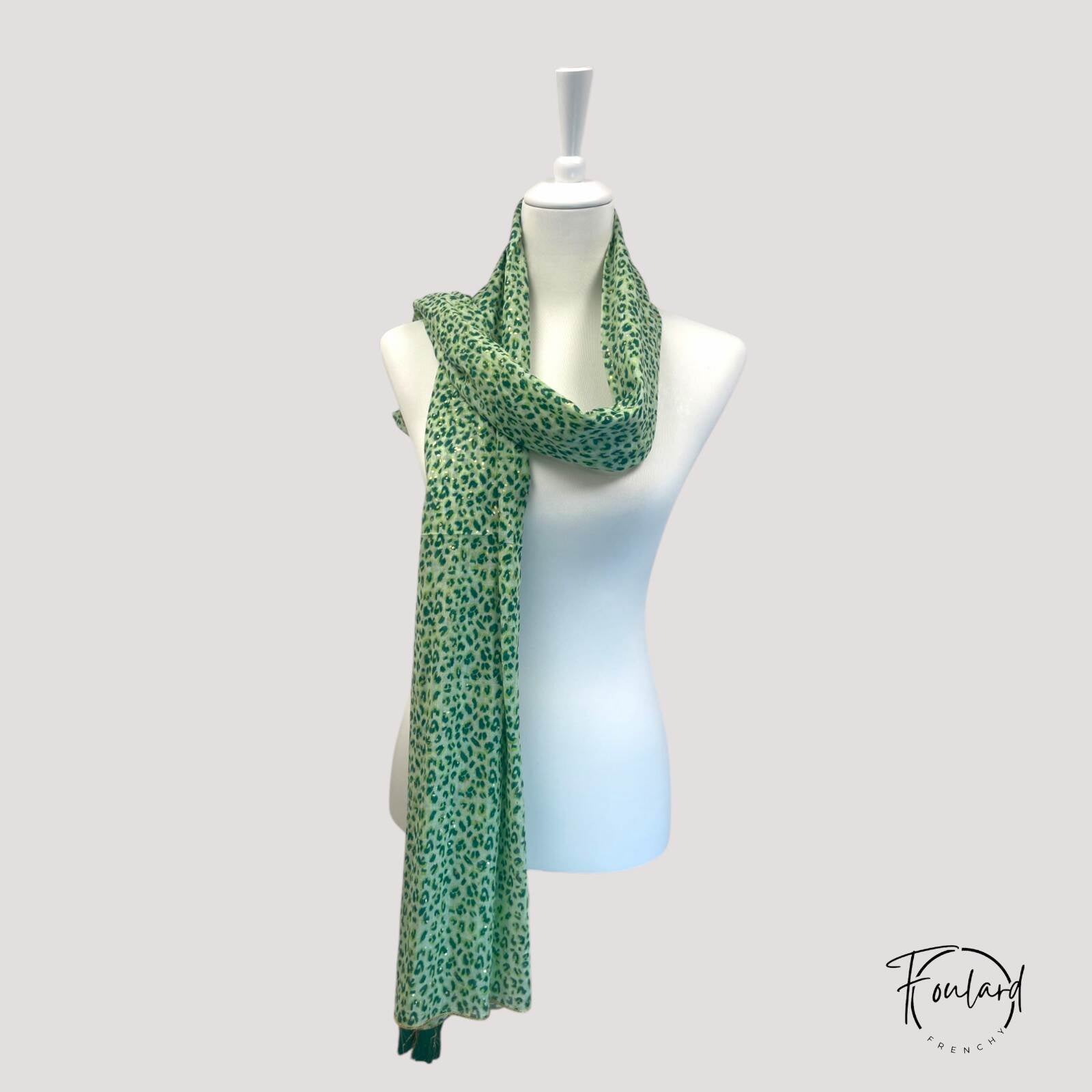 Vue rapprochée des pompons verts et dorés du foulard