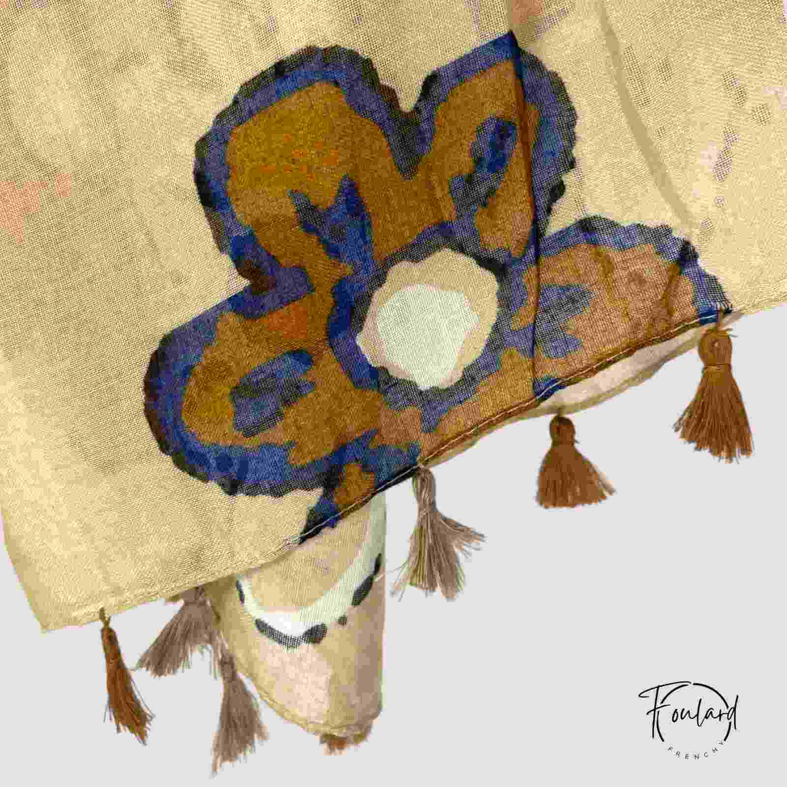 Foulard beige noué, mettant en valeur les motifs