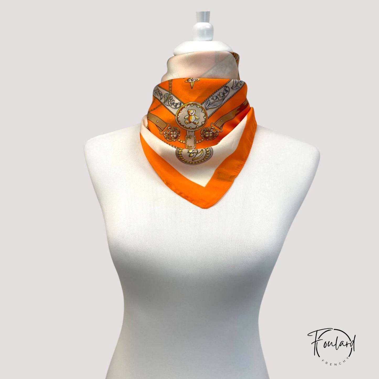 Foulard orange plié sur fond blanc, tissu doux visible