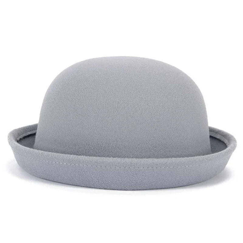 Chapeau melon noir, posé sur une chaise en bois, éclairé par une lampe