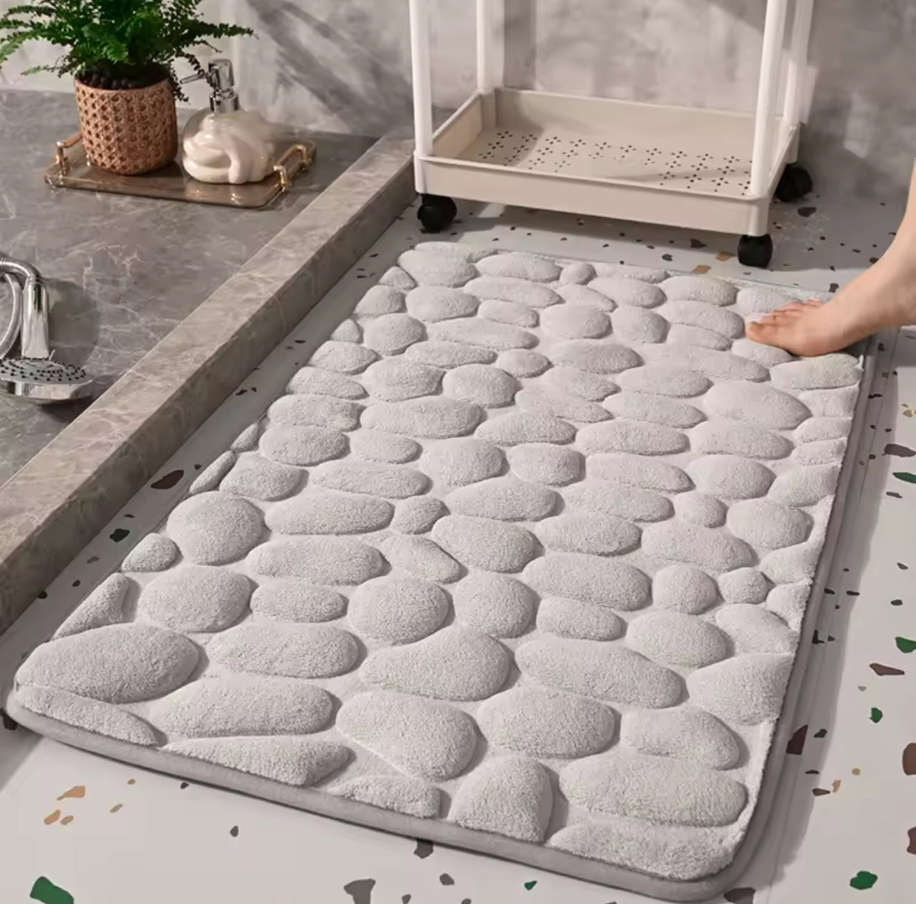 Tapis de bain galets sur sol carrelé, vue de dessus