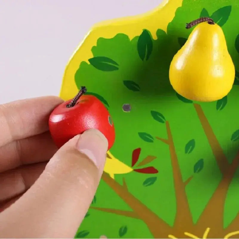 Enfant plaçant des fruits en bois sur un arbre éducatif