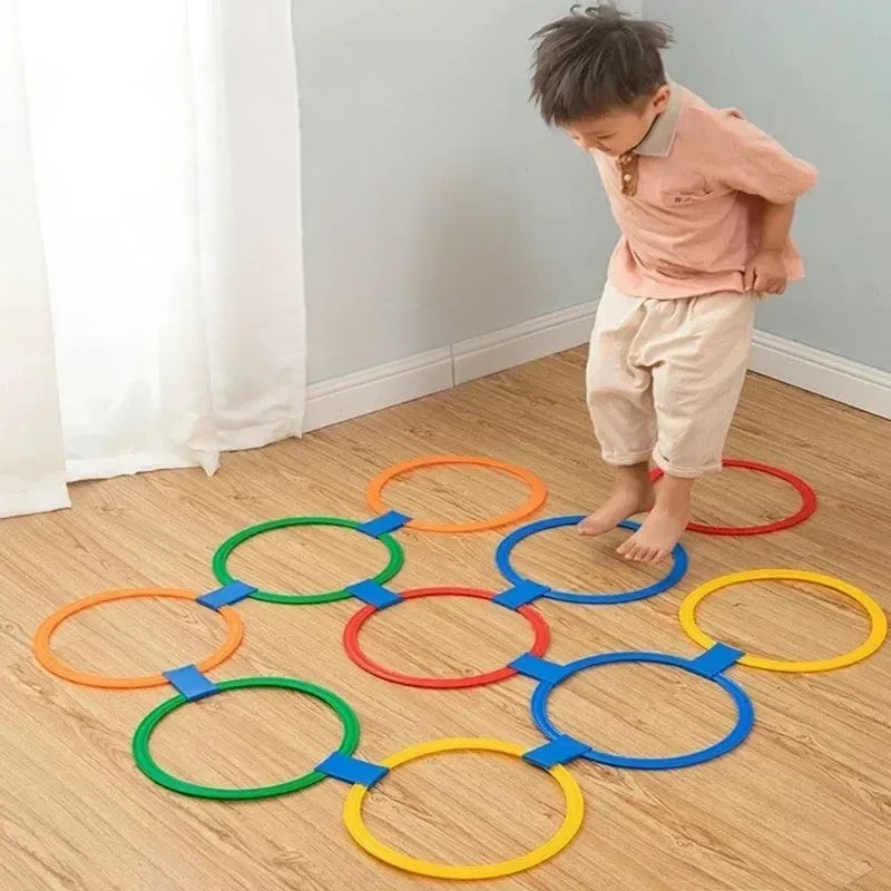 Enfant jouant avec des anneaux de saut colorés dans le jardin
