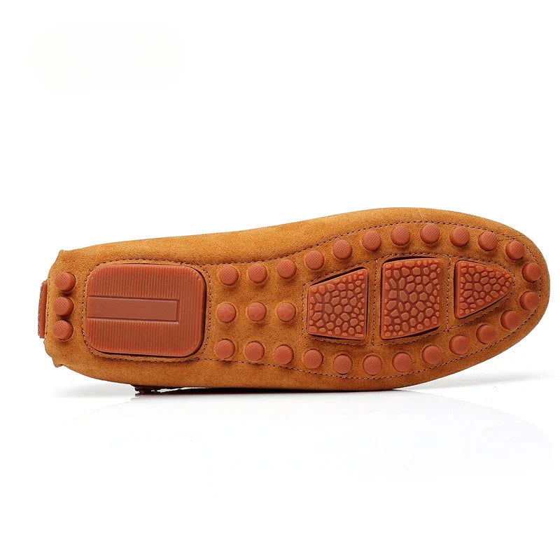 Mocassins en daim posés sur une surface en bois clair