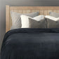 Plaid noir moelleux sur canapé clair, ambiance cocooning