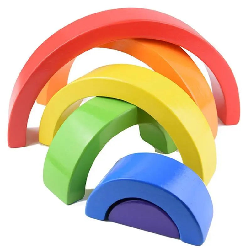 Main d'enfant empilant les arcs en bois colorés