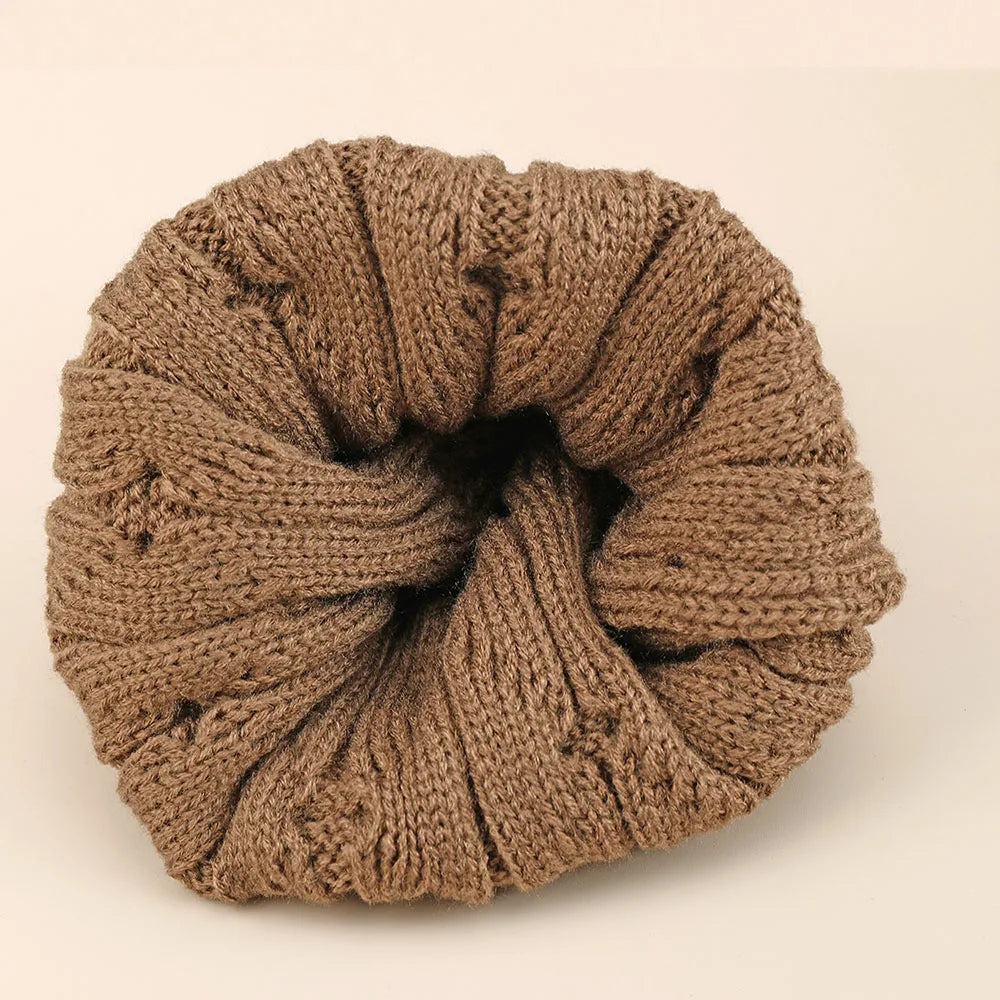 Bonnet torsadé en laine, couleur grise, posé sur une table