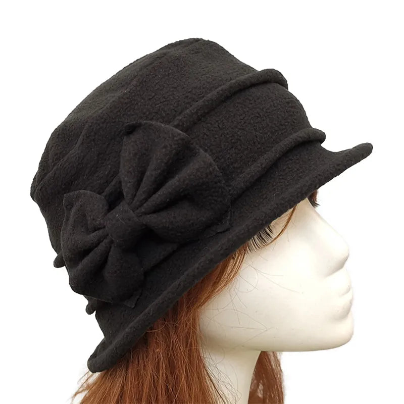 Chapeau cloche en feutre beige avec ruban noir, posé sur une table