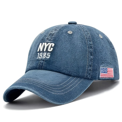 Casquette en denim posée sur une surface en bois, broderies en détail