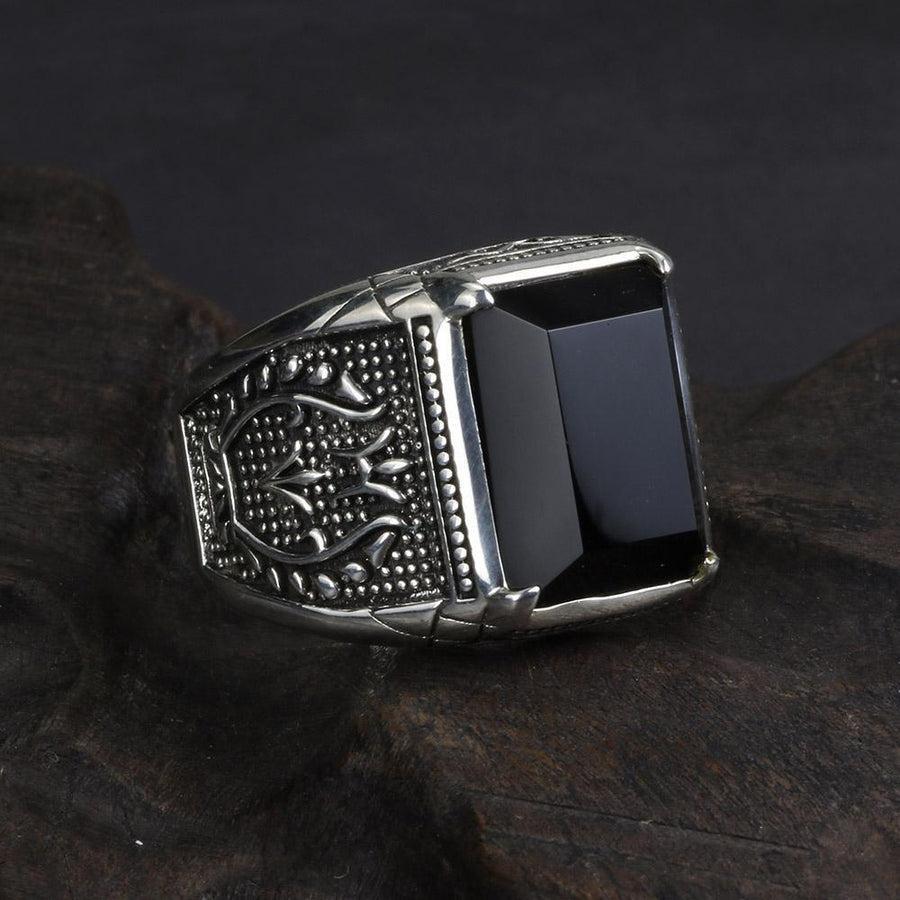 Bague en argent et obsidienne noire posée sur une surface blanche