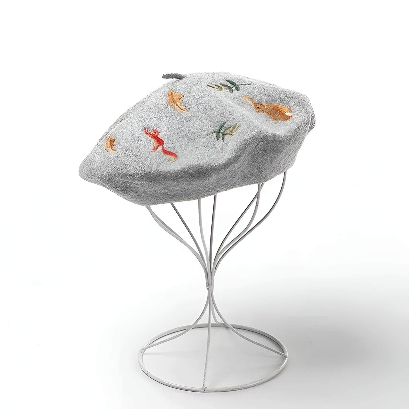 Béret en coton gris avec motif, posé sur une surface blanche