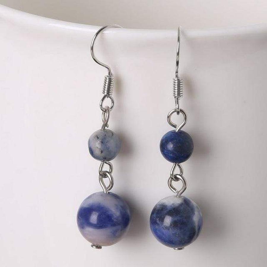 Boucles d'oreilles améthyste posées sur une surface claire