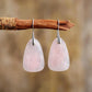 Boucles d'oreilles en quartz rose posées sur une surface claire