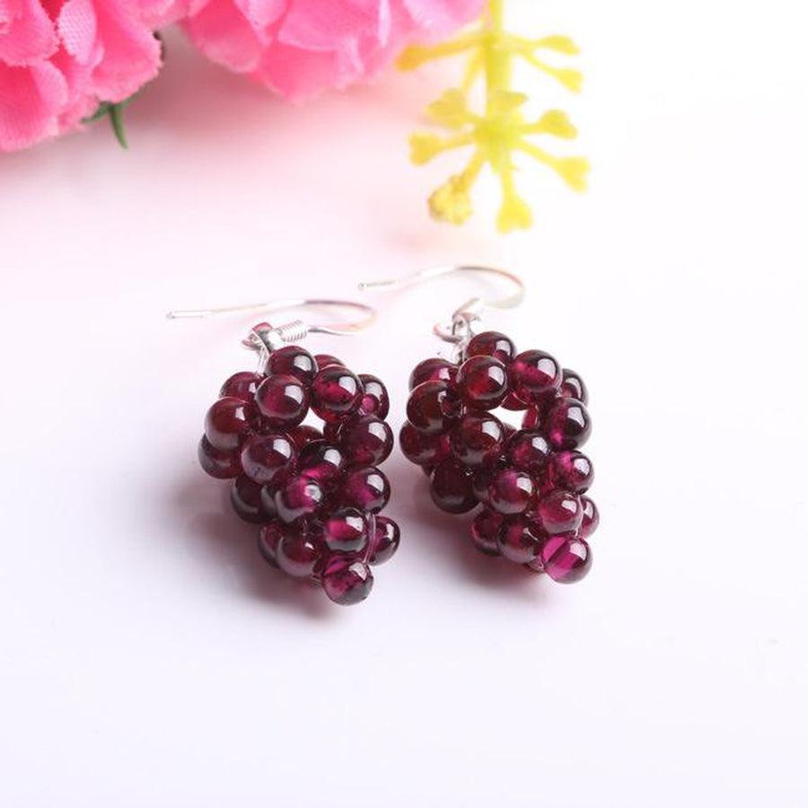 Boucles d'oreilles grenat en forme de grappe sur fond blanc