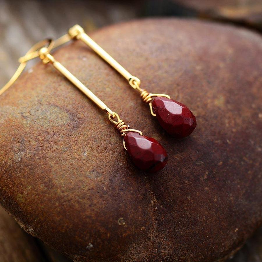 Boucles d'oreilles en jaspe rouge, élégamment présentées sur un support