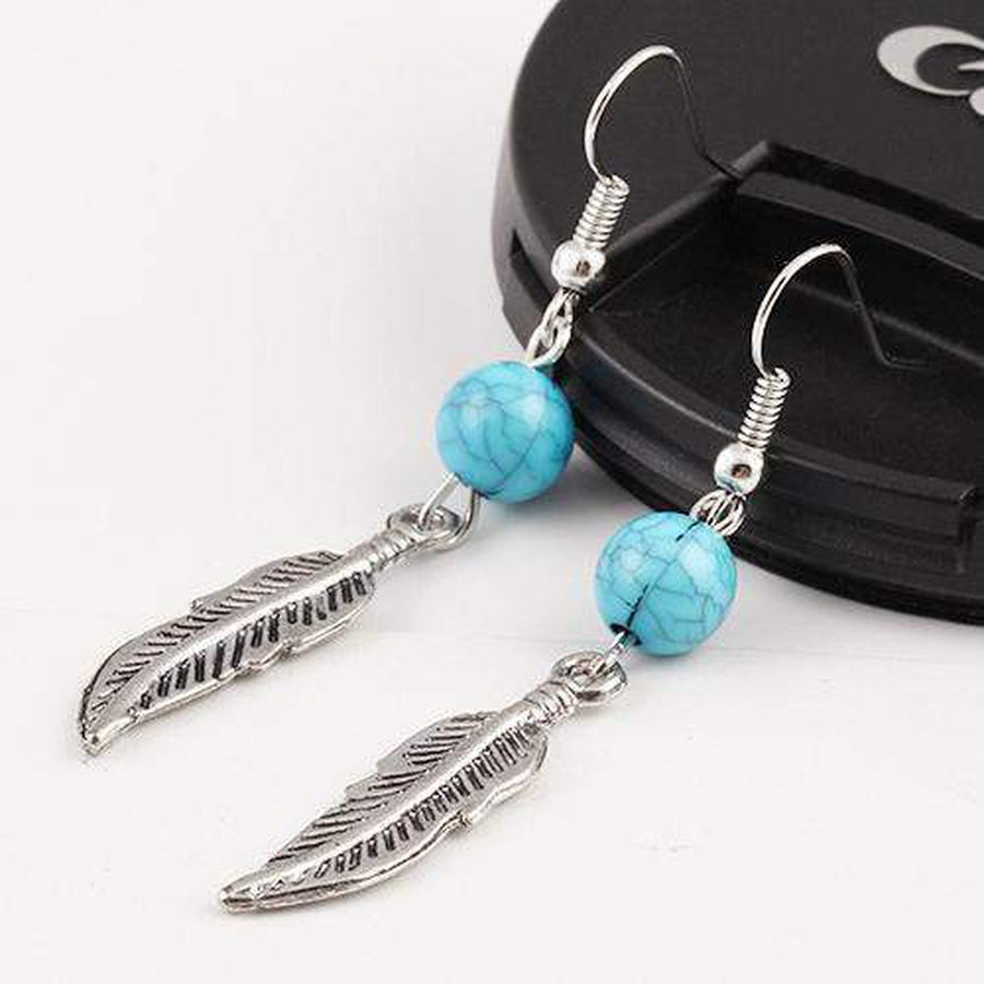Ensemble de boucles d'oreilles plume turquoise sur fond neutre