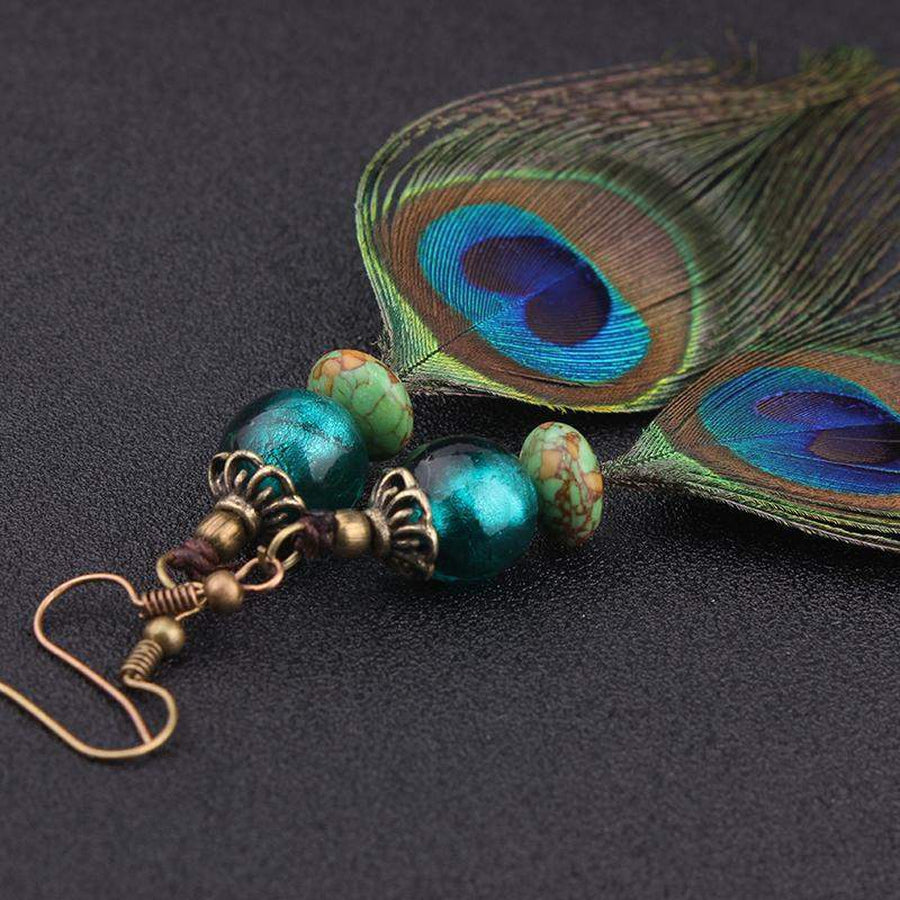 Détail des plumes de paon aux reflets irisés sur les boucles