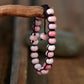 Bracelet en opale rose sur fond blanc, cordon noir visible
