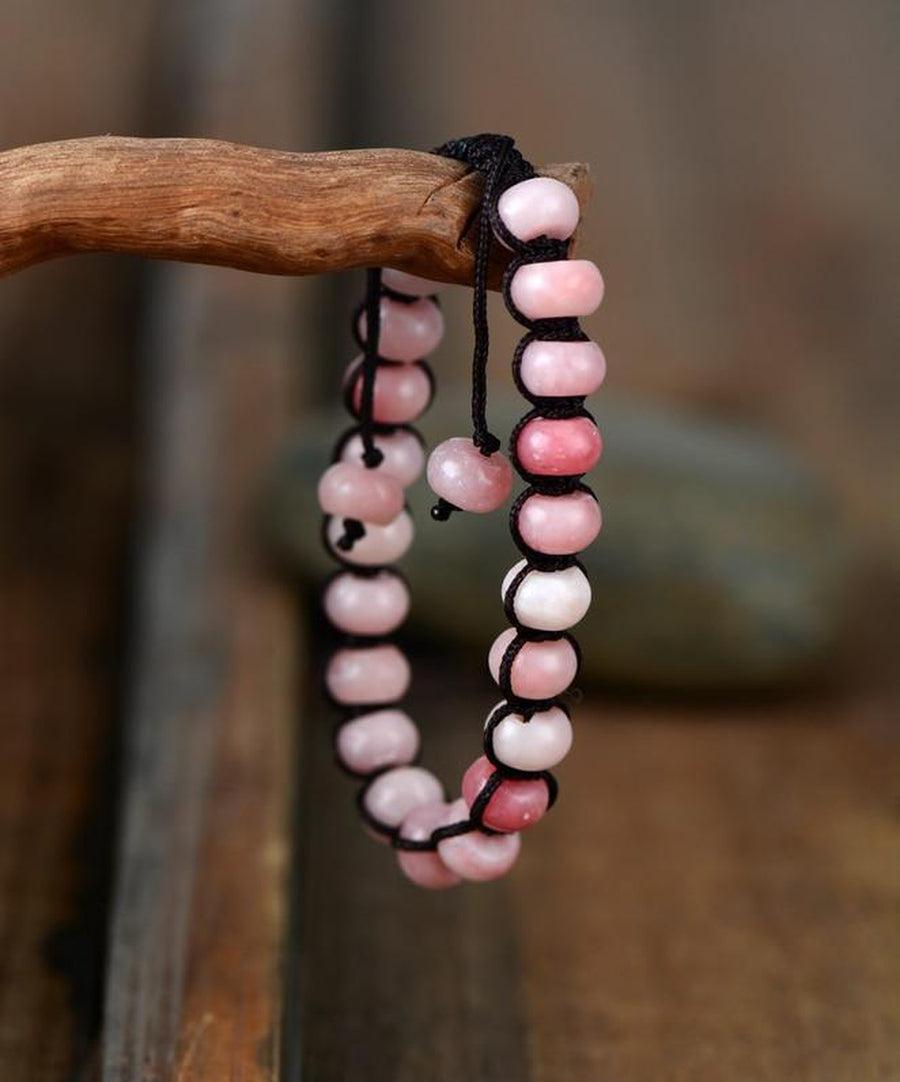 Bracelet en opale rose sur fond blanc, cordon noir visible